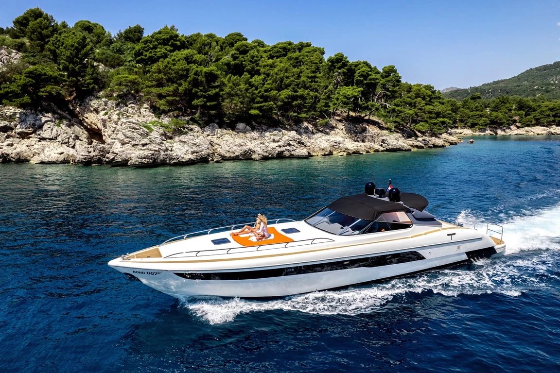 Bond 007 luxury sport yacht cruising past a pine-lined cove near Dubrovnik