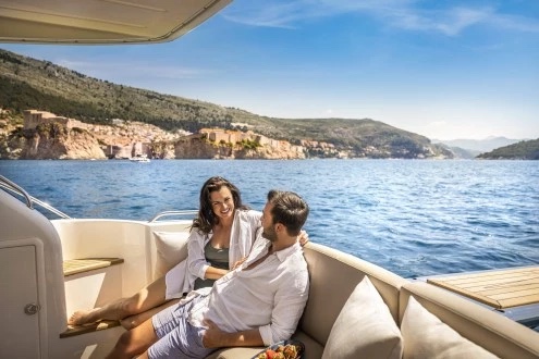 Couple relaxing on the Fairline Phantom 40's aft cockpit sofa, old city walls across the water behind them