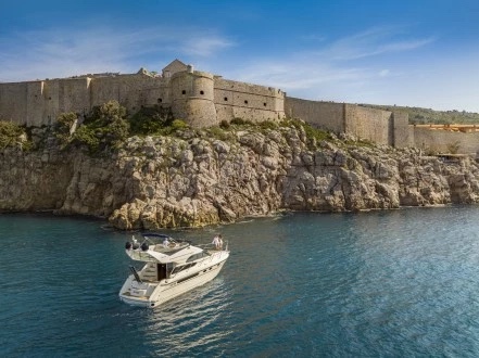 Fairline Phantom 40 cruising beneath the medieval city walls on a clear summer day