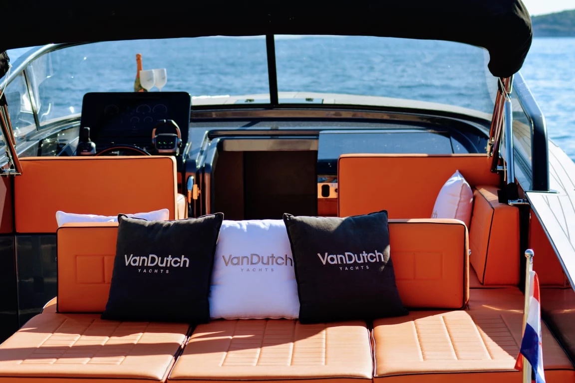 Cockpit of the VanDutch 32 with burnt-orange leather seating, branded cushions and the helm under a black bimini
